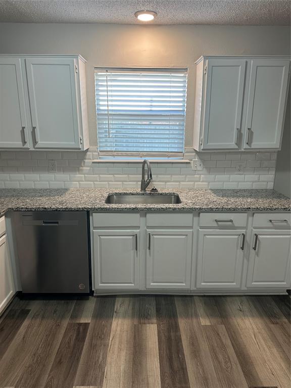 kitchen featuring dark wood finished floors, a sink, white cabinetry, and stainless steel dishwasher