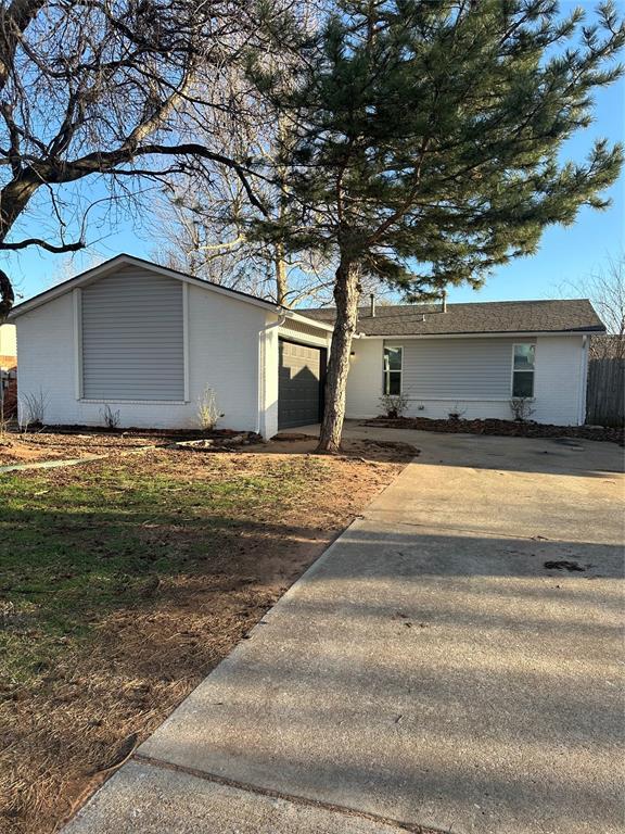 view of front of property with concrete driveway, an attached garage, and fence