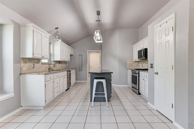 kitchen with light tile patterned floors, a sink, vaulted ceiling, appliances with stainless steel finishes, and a center island