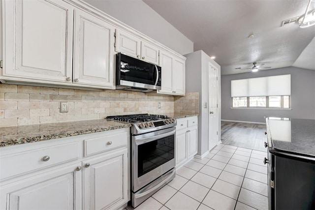 kitchen featuring stainless steel appliances, white cabinets, light tile patterned floors, decorative backsplash, and ceiling fan