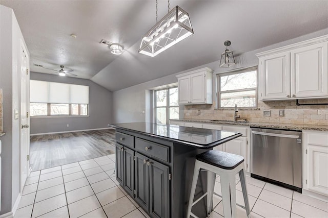 kitchen with a sink, white cabinetry, light tile patterned floors, lofted ceiling, and dishwasher