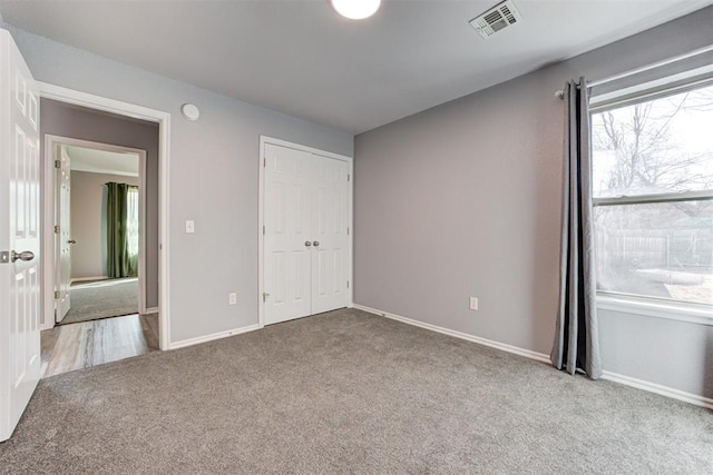 unfurnished bedroom featuring a closet, visible vents, carpet flooring, and baseboards