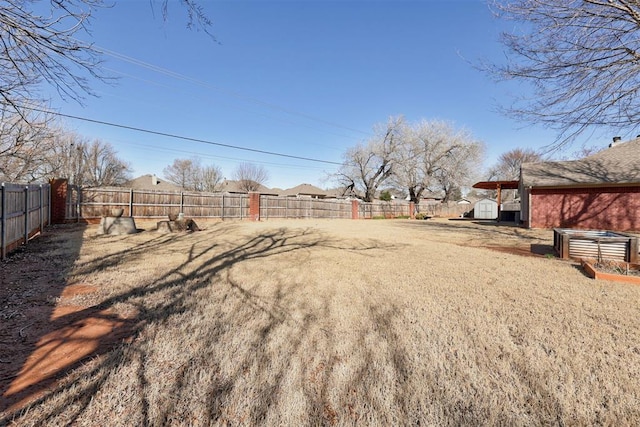 view of yard featuring an outbuilding, a fenced backyard, and a shed