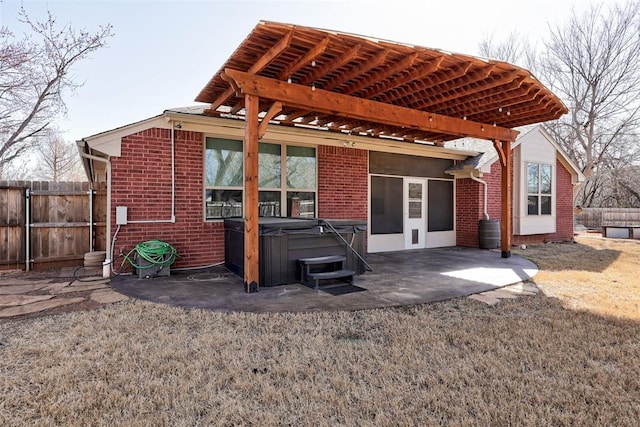 rear view of property featuring brick siding, a hot tub, fence, a patio area, and a pergola