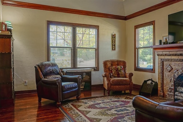 sitting room with a textured wall, a stone fireplace, baseboards, and wood finished floors