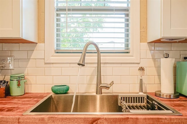 interior details with a sink, decorative backsplash, and white cabinets