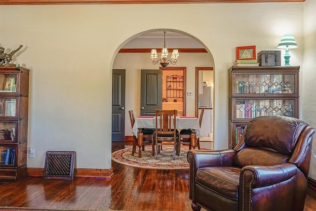 sitting room featuring hardwood / wood-style floors, arched walkways, crown molding, baseboards, and a chandelier