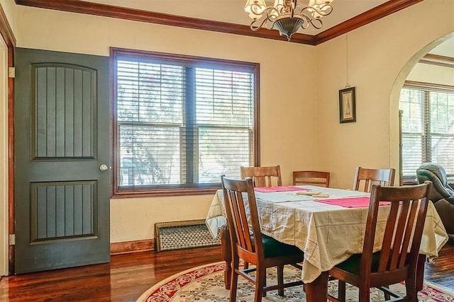 dining area with wood finished floors, arched walkways, a chandelier, and ornamental molding
