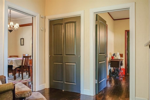 hallway with a chandelier, baseboards, dark wood finished floors, and ornamental molding