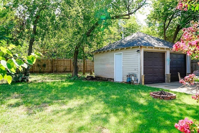 view of yard featuring a detached garage, fence, an outdoor fire pit, an outdoor structure, and a patio area