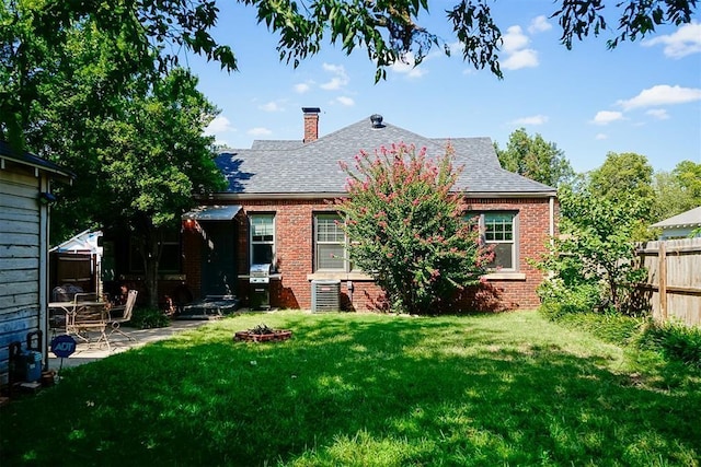 back of house featuring fence, a chimney, a lawn, a patio area, and brick siding