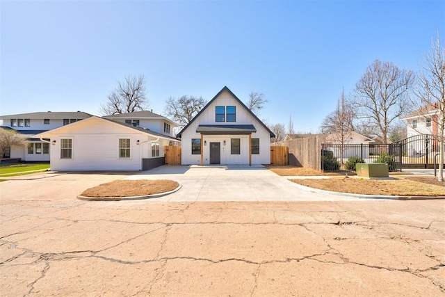 view of front of property featuring fence, board and batten siding, driveway, and a gate