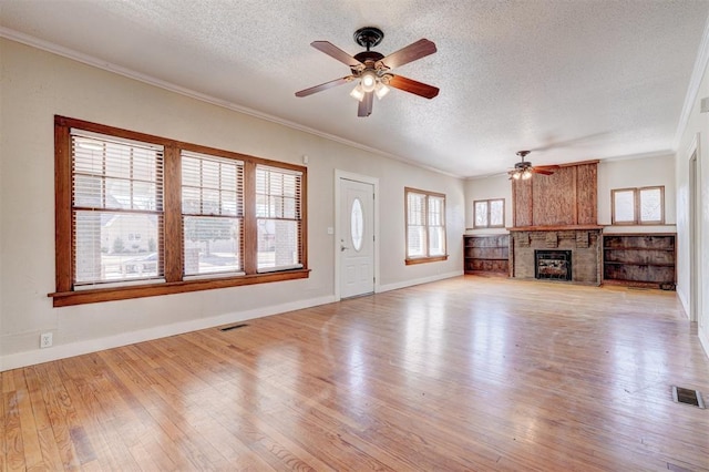 unfurnished living room with visible vents, a fireplace, crown molding, and wood finished floors