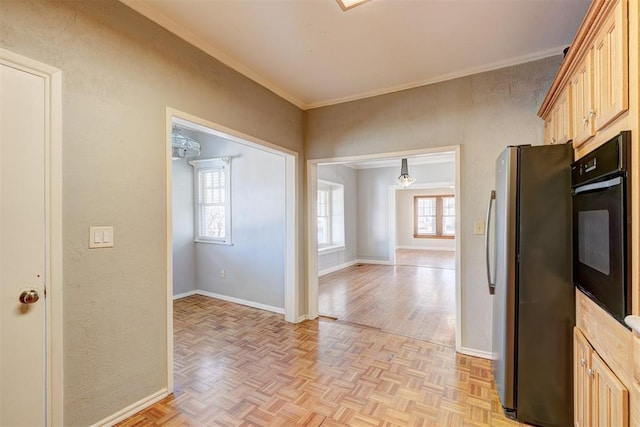 kitchen featuring baseboards, freestanding refrigerator, parquet flooring, crown molding, and black oven