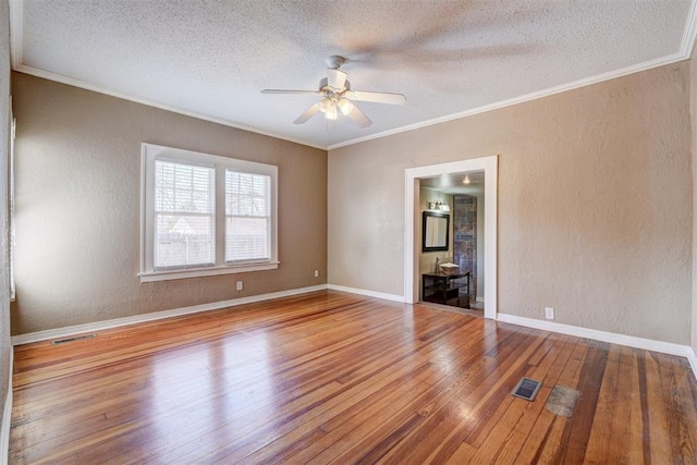 unfurnished room with visible vents, hardwood / wood-style flooring, crown molding, and a textured wall