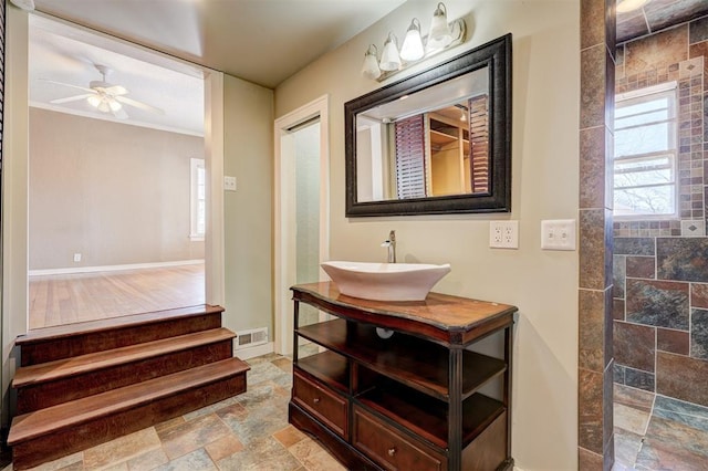 bathroom featuring visible vents, a walk in shower, stone tile flooring, vanity, and a ceiling fan