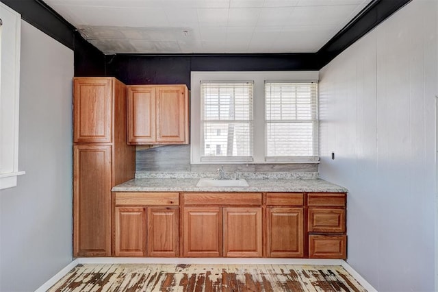 kitchen with brown cabinetry, baseboards, and a sink