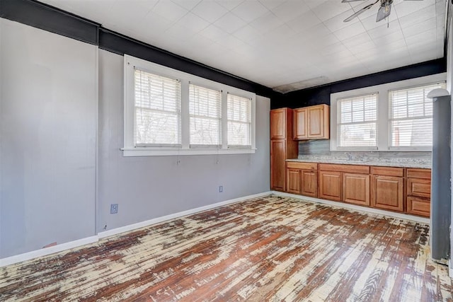 kitchen featuring baseboards, a sink, light countertops, light wood-style floors, and brown cabinets