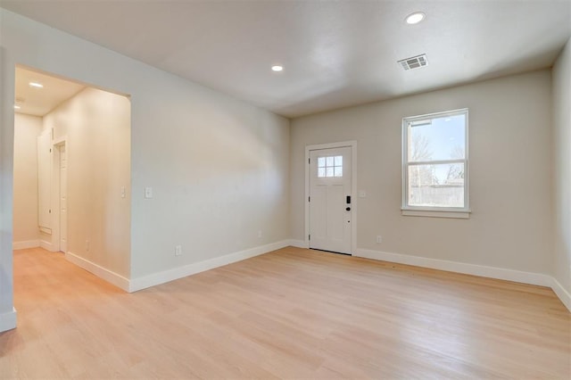 foyer entrance featuring baseboards, visible vents, and light wood finished floors