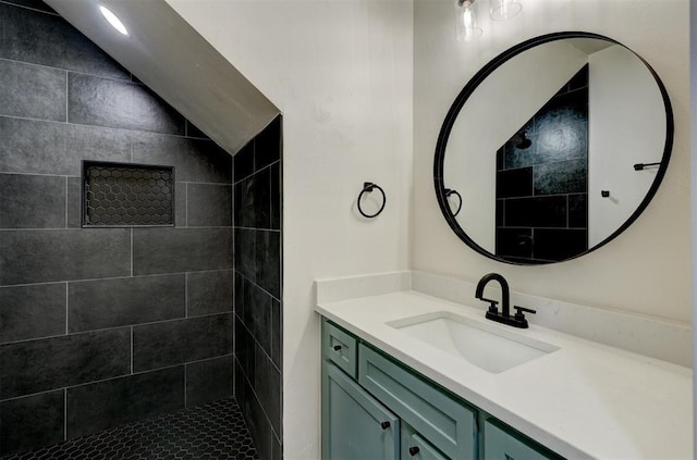 bathroom featuring a tile shower, vanity, and lofted ceiling