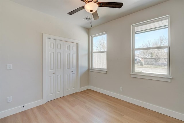 unfurnished bedroom featuring visible vents, baseboards, ceiling fan, light wood-style flooring, and a closet