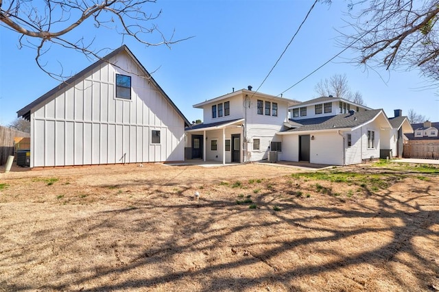 rear view of house featuring board and batten siding, a patio, and fence