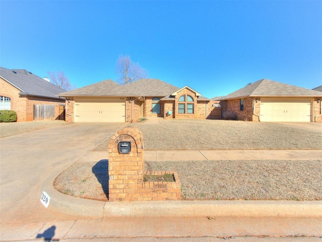 ranch-style home featuring brick siding, driveway, a garage, and fence