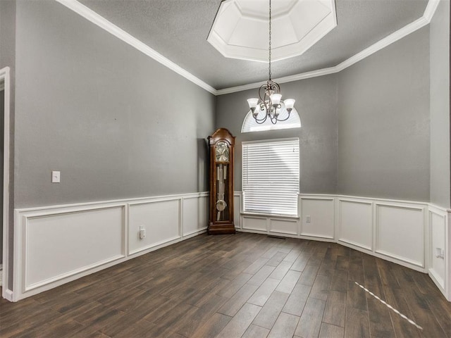 spare room with a wainscoted wall, an inviting chandelier, dark wood-style flooring, a textured ceiling, and crown molding