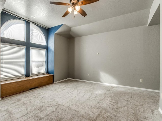 carpeted spare room featuring baseboards, lofted ceiling, a textured ceiling, and a ceiling fan