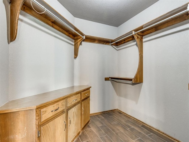 walk in closet with wood finish floors