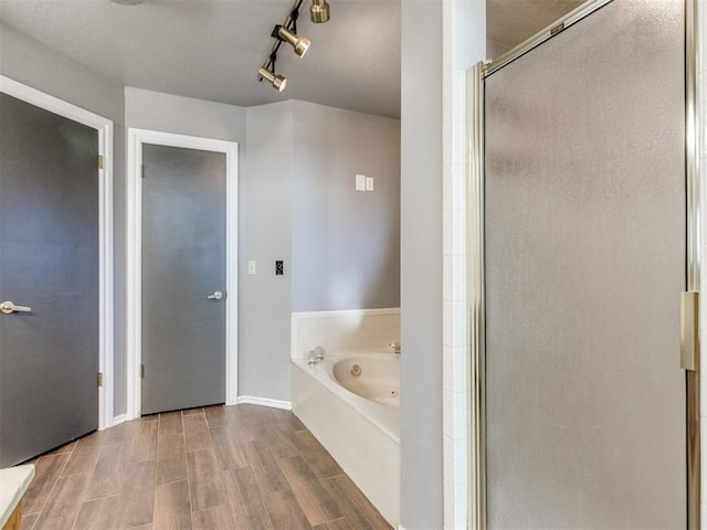 full bath featuring a tub with jets, baseboards, wood tiled floor, a shower stall, and track lighting