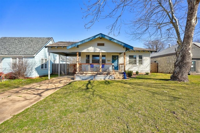 view of front of house featuring a front lawn, fence, covered porch, concrete driveway, and a carport