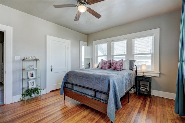 bedroom featuring a ceiling fan, baseboards, and wood finished floors