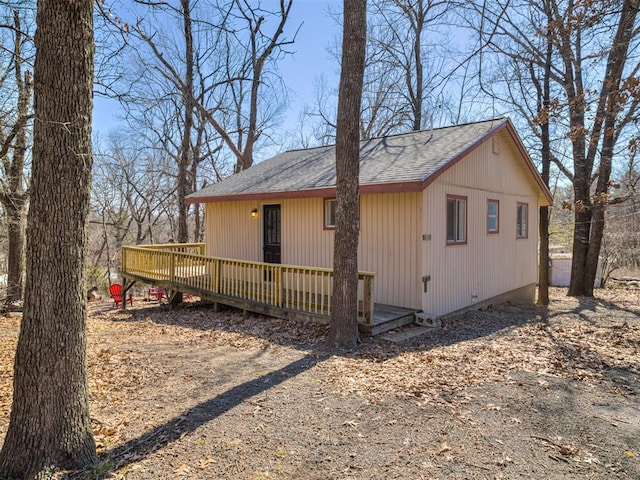 exterior space with a shingled roof and a deck