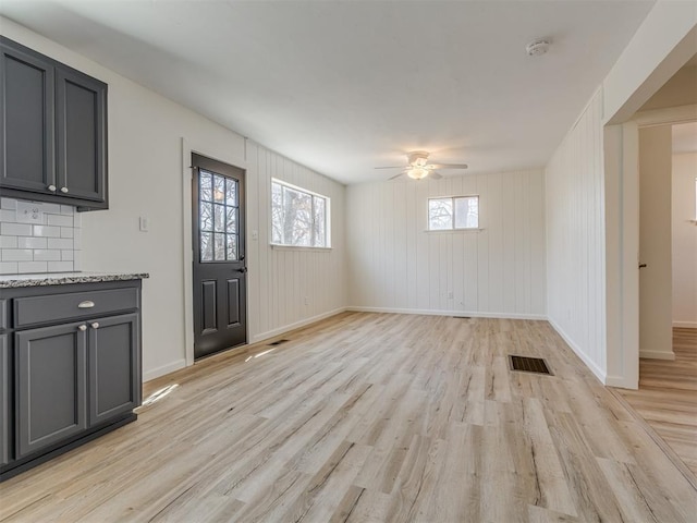 interior space with light wood-type flooring, visible vents, baseboards, and ceiling fan