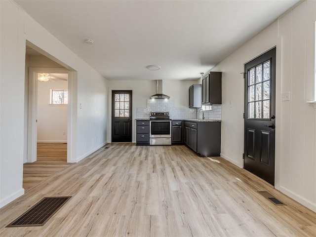 kitchen featuring electric range, wall chimney exhaust hood, visible vents, and light wood-type flooring