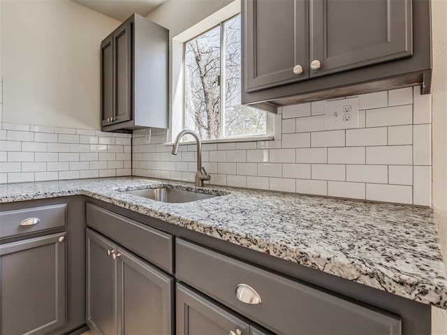 kitchen featuring backsplash, gray cabinetry, and a sink