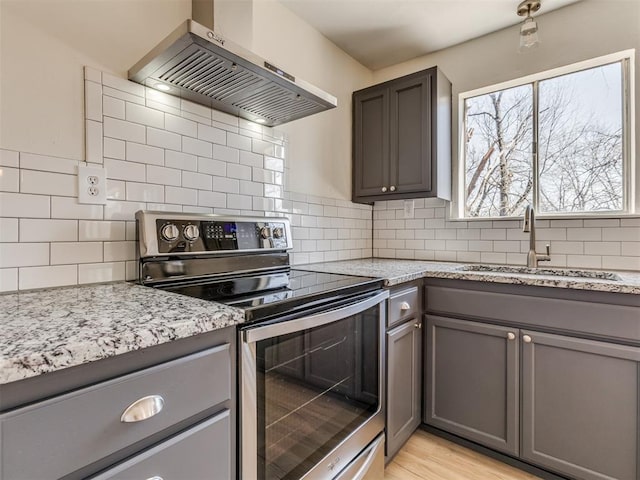 kitchen with a sink, stainless steel electric range oven, wall chimney exhaust hood, and gray cabinets