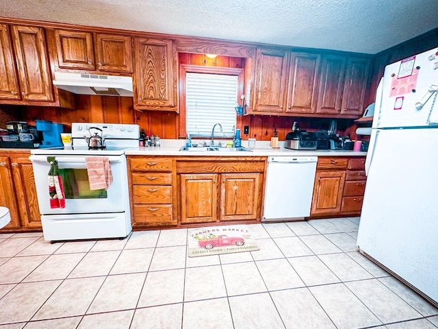 kitchen featuring white appliances, light countertops, under cabinet range hood, and a sink