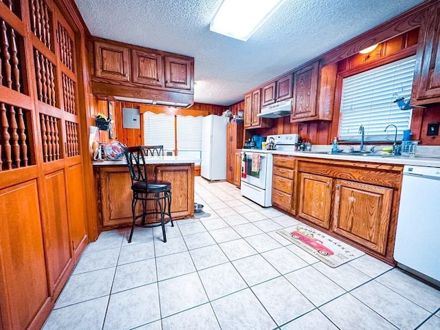 kitchen with under cabinet range hood, white appliances, light countertops, and a sink