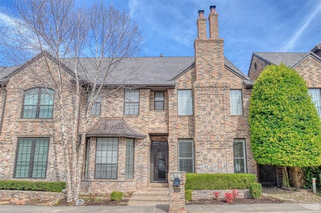 view of front of house featuring brick siding and a chimney