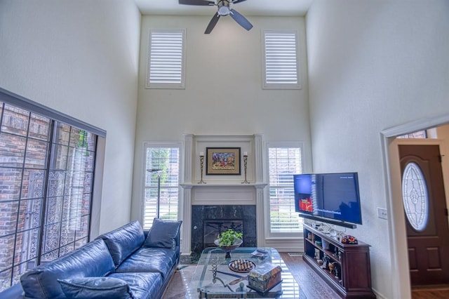 living room featuring a high end fireplace, plenty of natural light, a high ceiling, and a ceiling fan