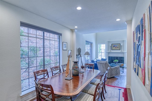 dining area featuring recessed lighting, a fireplace, baseboards, and wood finished floors