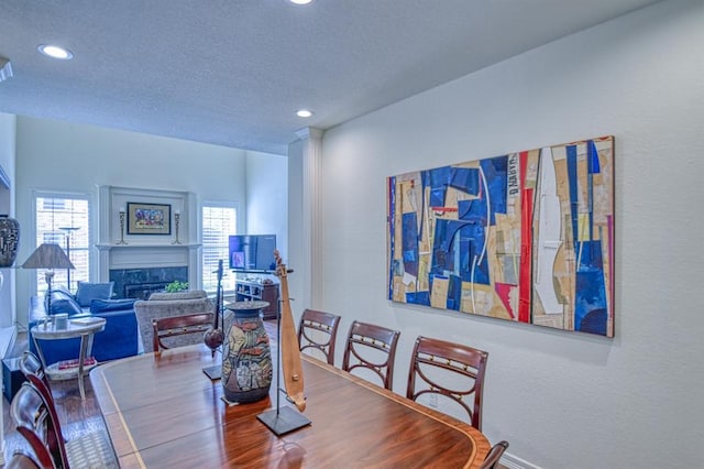 dining area with a high end fireplace, recessed lighting, and a textured ceiling