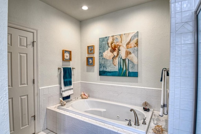 full bath featuring a jetted tub and a textured wall