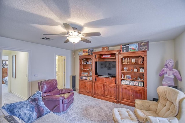 living area with visible vents, carpet floors, a textured ceiling, and a ceiling fan