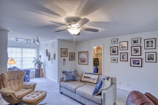 carpeted living area with baseboards, track lighting, a textured ceiling, and a ceiling fan