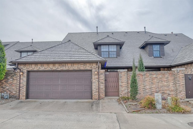 view of front of house with brick siding, concrete driveway, an attached garage, and fence