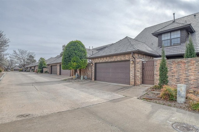 view of front of house featuring concrete driveway, an attached garage, and fence