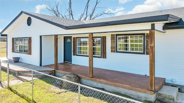 exterior space featuring a porch, a shingled roof, and fence